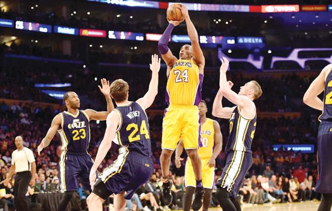 High and bye: Kobe Bryant of the Los Angeles Lakers goes up for a shot even as he is surrounded by three Utah Jazz players in his final NBA encounter at the Staples Center in Los Angeles, California yesterday. Pic/AFP