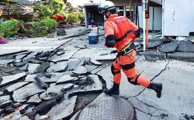 A rescue team member runs on a street cracked by the earthquake in Mashiki, Kumamoto prefecture