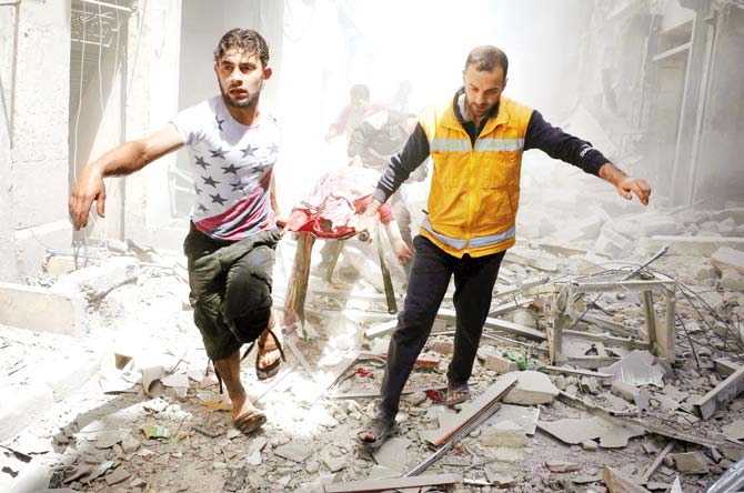 Syrian men carry a body on a stretcher amid the rubble of destroyed buildings following an air strike on the rebel-held neighbourhood of Al-Qatarji in Aleppo. Pic/AFP