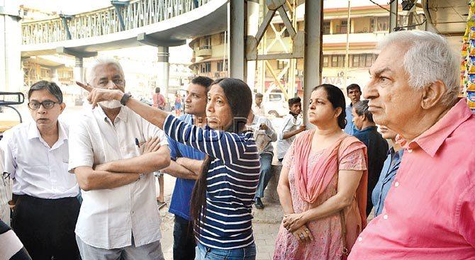 Viraj Kale (in striped T-shirt), a resident of Ishwardas Mansion, points out how the escalator closure is creating problems
