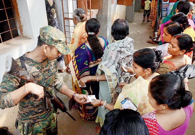 A Central Force jawan checks voter identity cards at a polling booth during the first phase of West Bengal Assembly Elections in West Medinipur