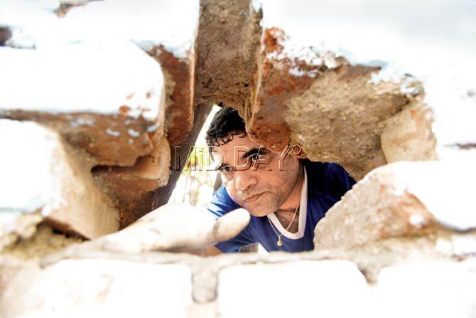 A man peers through the bricks in the wall. Pics/Suresh KK