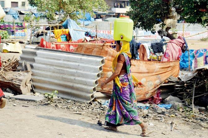 One of the migrant women carries a precious can of water to the settlement at Ghatkopar