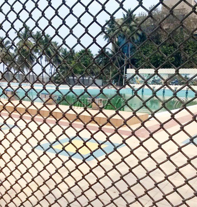 The non-functional pool seen through the fence