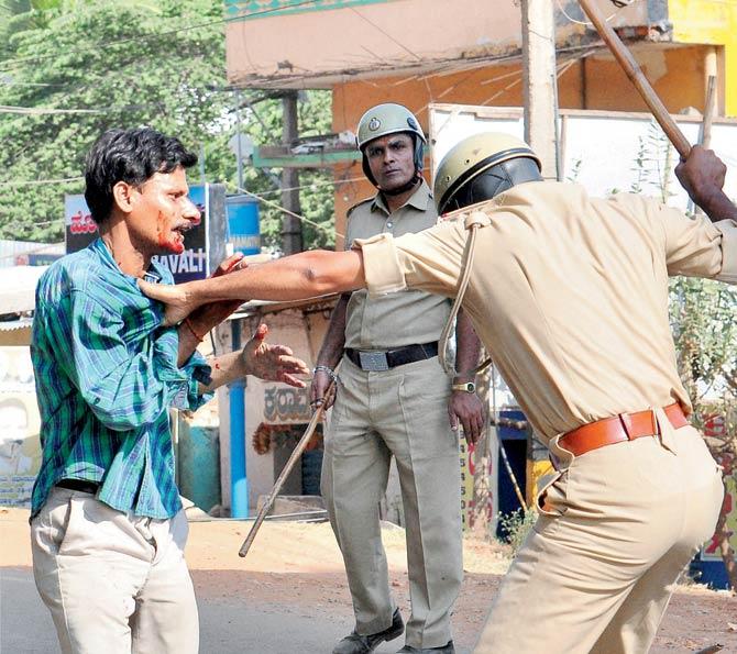 Police beating up one of the protesters. Pics/PTI