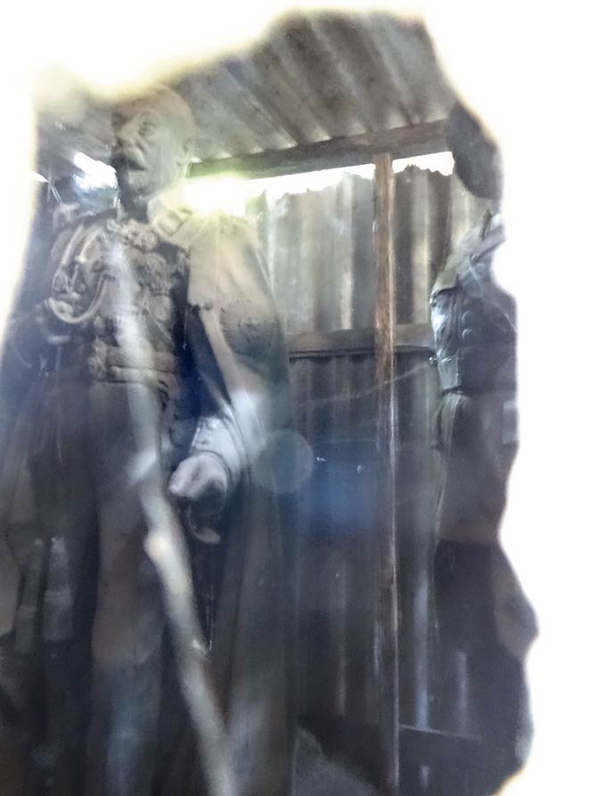 The statue visible through a chink in the shed