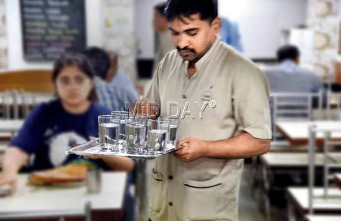 A waiter at Matunga’s Mysore Cafe carries a tray of ‘cutting’ water glasses. Pic/Sameer Markande