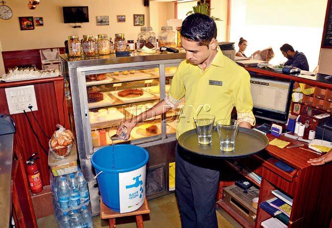 A waiter empties water, left over by a patron, into a bucket that will then be used to water plants on Chembur restaurant Le Cafe’s premises. Pic/Sayed Sameer Abedi