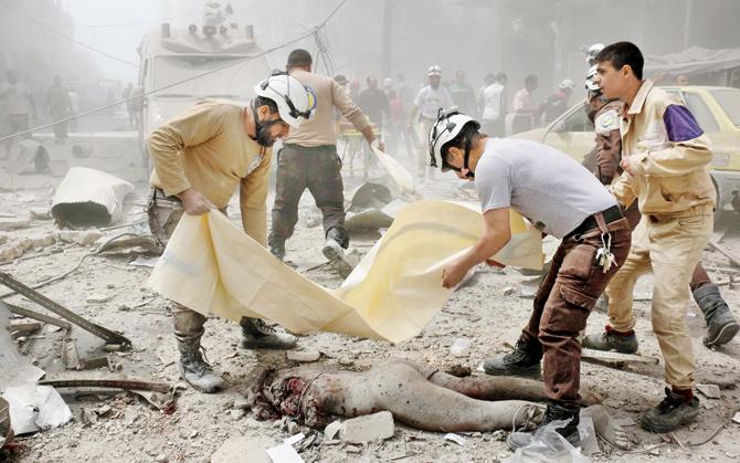 Civil defence volunteers wrap a body in a plastic bag after the air strike on the rebel-held neighbourhood of al-Kalasa in Aleppo. Pic/AFP