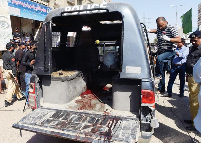 Security officials inspect the police van in which four cops were killed in Karachi. Pic/AFP