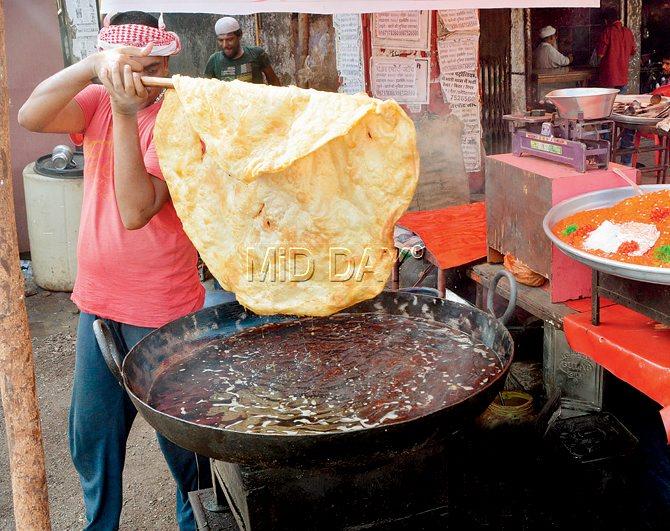 A staffer prepares the puri, which is served with a sweet rawa halwa, outside Pankhe Shah Dargah in Ghatkopar 