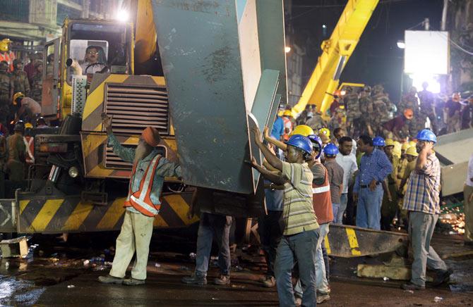 Indian rescue workers and volunteers try to free people trapped under the wreckage of a collapsed flyover in Kolkata