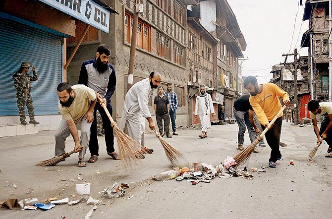 Volunteers and local residents launch a cleanliness drive during curfew in Srinagar yesterday. Pic/PTI