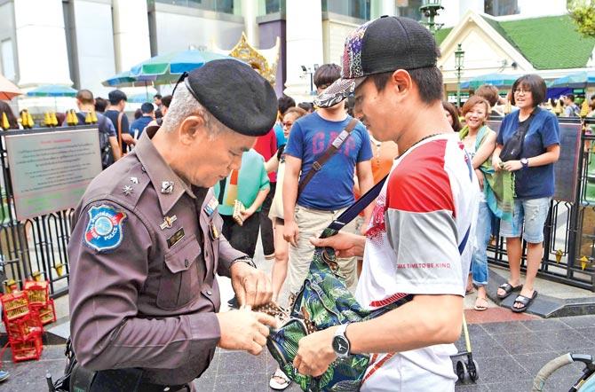 On alert: A Thai policeman searches a visitor