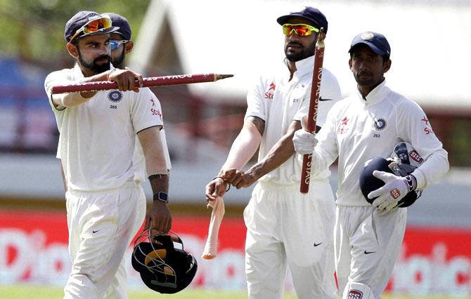 India-s captain Virat Kohli, left, shows the wicket as he leaves the field with wicketkeeper Wriddhiman Saha, right, and Shikhar Dhawan after defeating West Indies for 237 runs during day five of their third cricket Test match at the Daren Sammy Cricket Ground in Gros Islet, St. Lucia