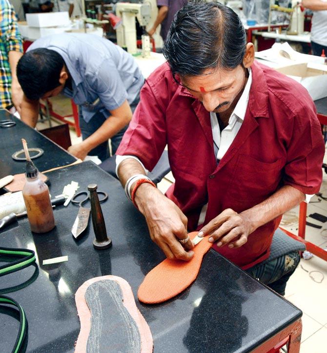 Another worker puts new soles on old footwear for better use