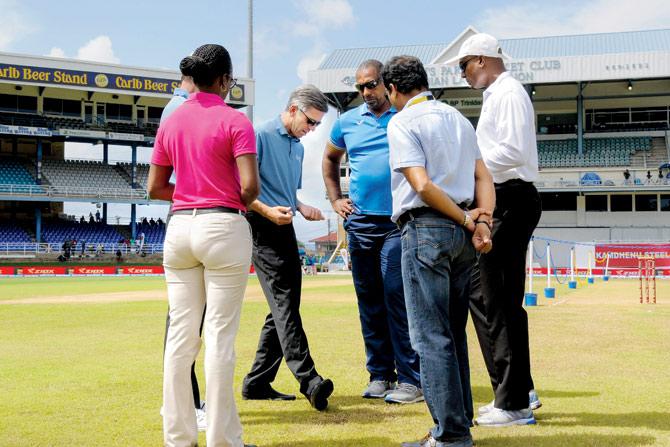 Match officials inspecting the outfield on Day Four in Port of Spain yesterday. PIC/AFP