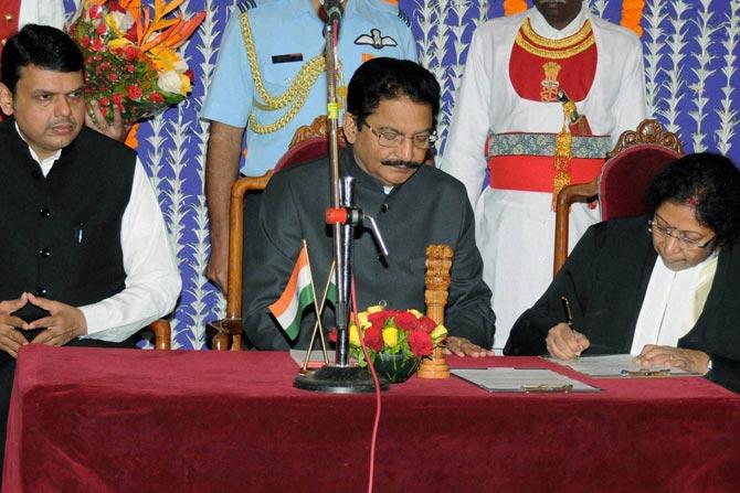 Governor of Maharashtra Ch Vidhyasagar Rao and CM Devendra Fadnavis look on as Chief Justice of Bombay High Court Justice Manjula Chellur signs a register at her swearing-in ceremony at Raj Bhavan in Mumbai. Pic/ PTI