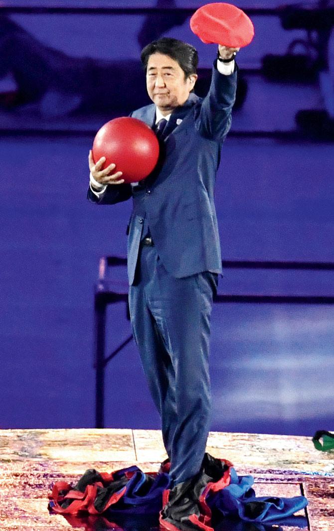 Japan’s Prime Minister Shinzo Abe takes off his Super Mario costume while Japanese dancers (above) ring in the beginning of the next Olympics journey — Tokyo 2020