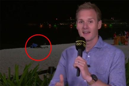 Awkward! Couple caught getting cosy behind presenter on live TV!