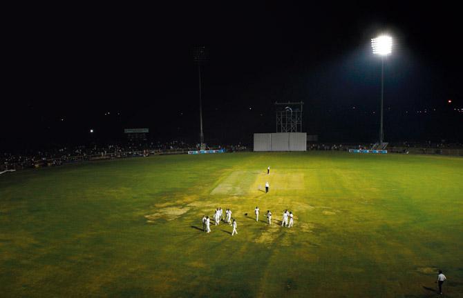 Players make their way back to the pavilion as floodlights go off in one section of the ground in Greater Noida during the opening Duleep Trophy game between India Red and India Green yesterday. Pic/AFP