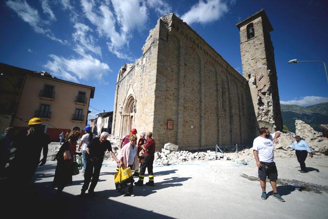 People walk past an earthquake damaged church during search and rescue operations in Amatrice on August 24, 2016 after a powerful earthquake rocked central Italy. Pic AFP