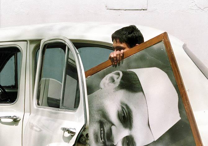 A youth shown in a photo dated 22 May 1991 removing a campaign poster of assassinated former Indian Prime Minister Rajiv Gandhi from the residence of the slain leader in the Indian capital. PICs/AFP