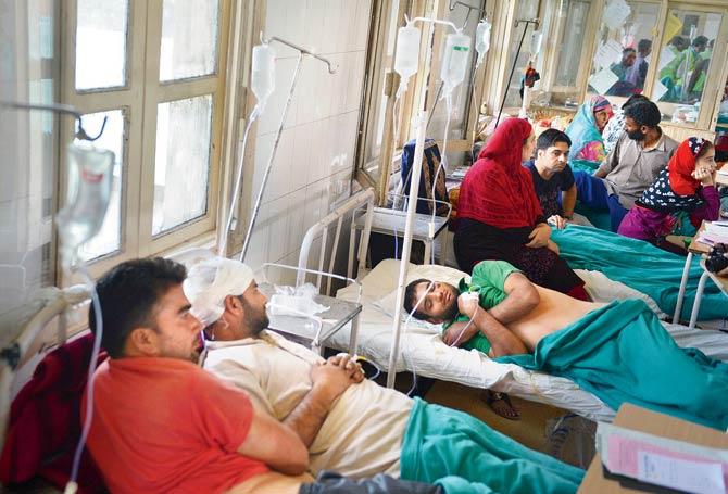 Injured Kashmiris being comforted by relatives in hospital beds in Srinagar. Pic/PTI
