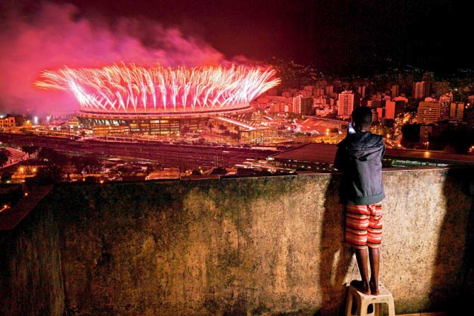 A boy from a slum in Mangueira watches fireworks over Maracana Stadium during the 2016 Olympics closing ceremony in Rio de Janeiro on Sunday. Pic/AFP
