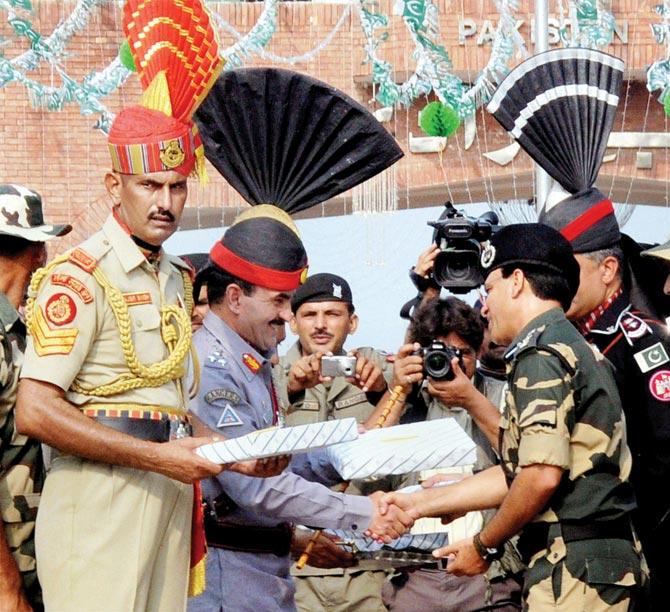 Pakistani Rangers sector Commander Shaukat Ali presents sweets to BSF Commandant Sudeep on the occasion of Pakistan’s Independence Day at the Attari-Wagah border yesterday. Pic/PTI