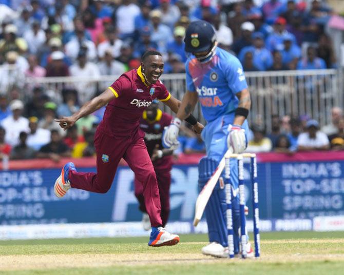 Dwayne Bravo (L) of West Indies celebrates the dismissal of Virat Kohli (R) of India during the 1st T20i between West Indies and India at Central Broward Stadium in Fort Lauderdale, Florida. / AFP PHOTO