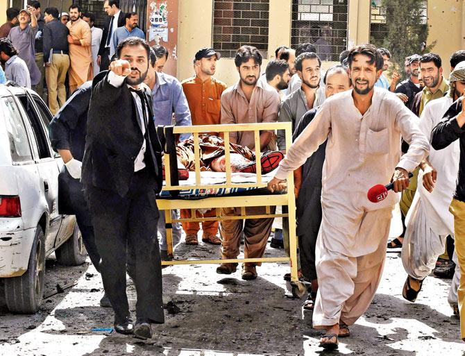 Pakistani lawyers and local media personnel carry a bed to move the body of a news cameraman after the explosion. Pic/AFP