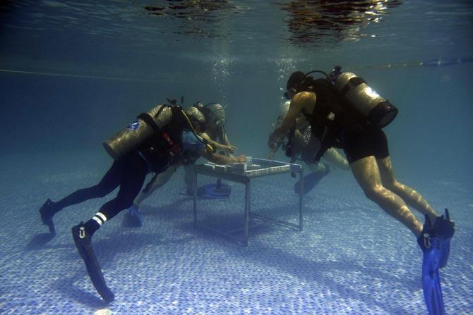These pictures show mahjong enthusiasts playing mahjong under water in a swimming pool at a diving club in the Chinese city of Chongqing