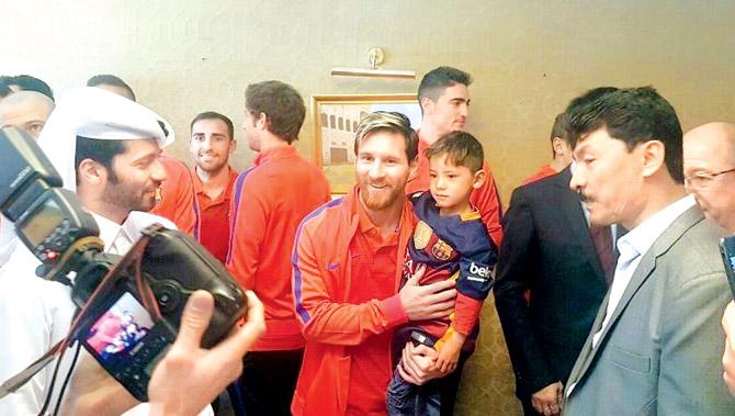 Lionel Messi (centre) holds six-year-old Afghan boy Murtaza Ahmadi in Doha yesterday, upon the team
