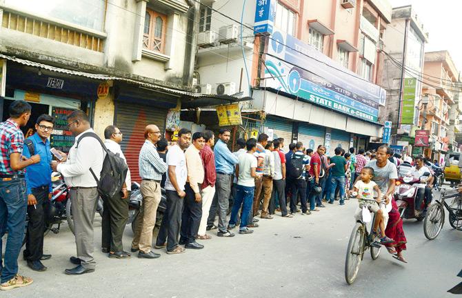 Over a month after the demonetisation drive began, queues are still a common sight outside banks and ATMs. Pic/AFP