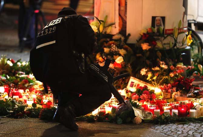 A policeman lights a candle on December 20, 2016 at a makeshift memorial in front of the Kaiser-Wilhelm-Gedaechtniskirche (Kaiser Wilhelm Memorial Church) in Berlin