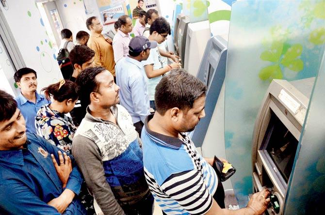 People wait to withdraw from a Navi Mumbai ATM on payday. Pic/PTI
