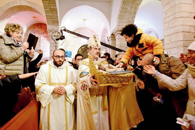 Archbishop Pierbattista Pizzaballa holds up an idol of Baby Jesus in St Catherine’s Church after the Christmas Midnight Mass and walks in procession to the ‘Grotto’, believed to be the birth place of Jesus Christ in Bethlehem, West Bank. Pic/AFP