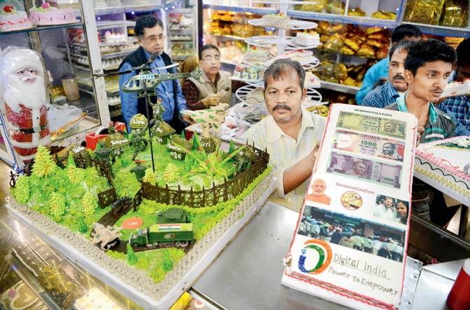 A shopkeeper holds up a cake prepared on the theme of demonetisation on Christmas eve in Siliguri. Pic/AFP