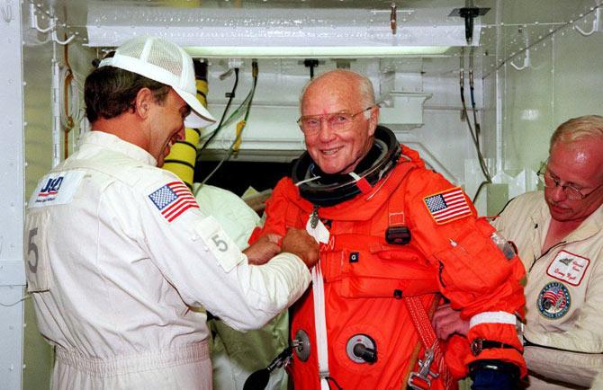 This file photo taken on October 9, 1998 shows US astronaut and Senator John Glenn getting a hand from white room technicians moments before boarding the US space shuttle Discovery. / AFP PHOTO / NASA / HO