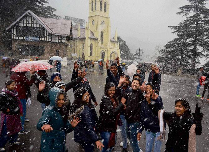 Tourists enjoy first snowfall of the season on the Christmas eve, in Shimla on Sunday. PTI 