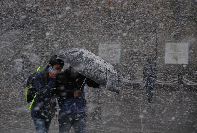 Pedestrians take shelter under an umbrella as they walk through heavy snowfall on a road in Shimla on Christmas Day. Pic/AFP 