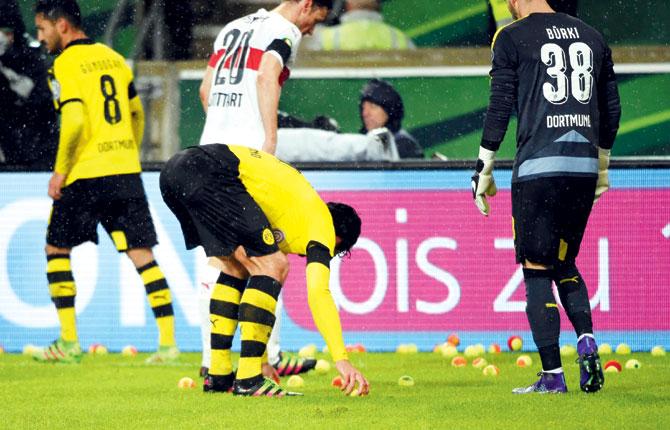 Dortmund players picks up tennis balls thrown by fans to protest against football matches ticket prices during the German Cup DFB Pokal quarter-final match against VfB Stuttgart on Tuesday. Pic/AFP
