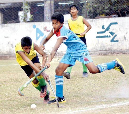 A Don Bosco (blue) player vies for the ball with a St Stanislaus player during the MSSA boys U-14 hockey final. 