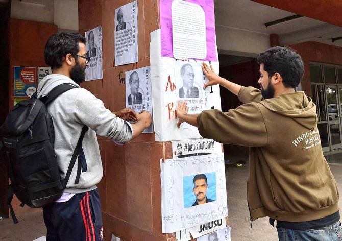 Students paste posters on the JNU campus. Pic/ PTI