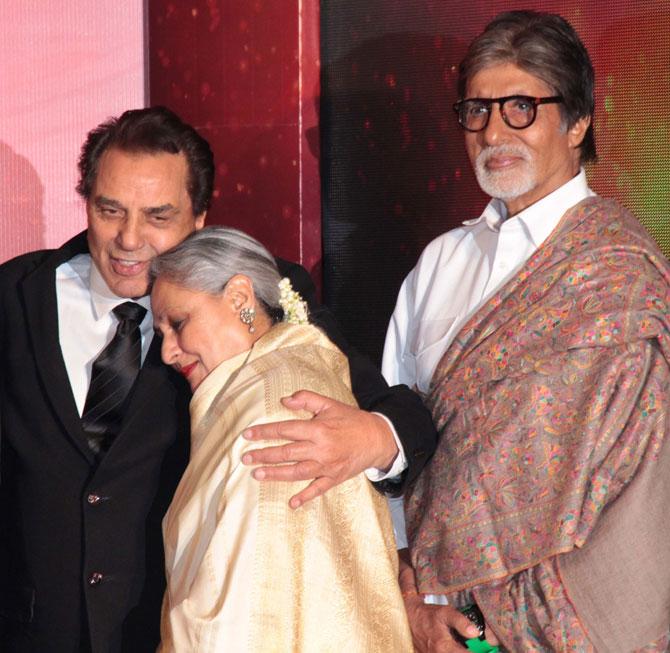 Dharmendra and Jaya Bachchan share a warm hug, while Amitabh Bachchan looks on