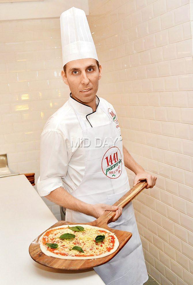 Chef Renato Viola readies to place a freshly made pizza into the oven