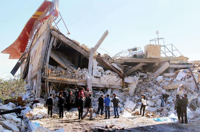 People gather around the rubble of a hospital supported in Syria after the building was hit by Russian air strikes. Pic/AFP