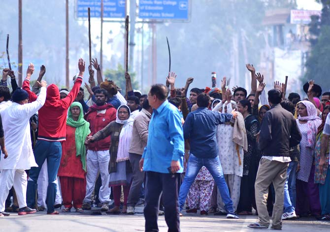 Residents gather on a street as others gesture to hold them back amid ongoing caste protests in Rohtak. AFP PHOTO / STR