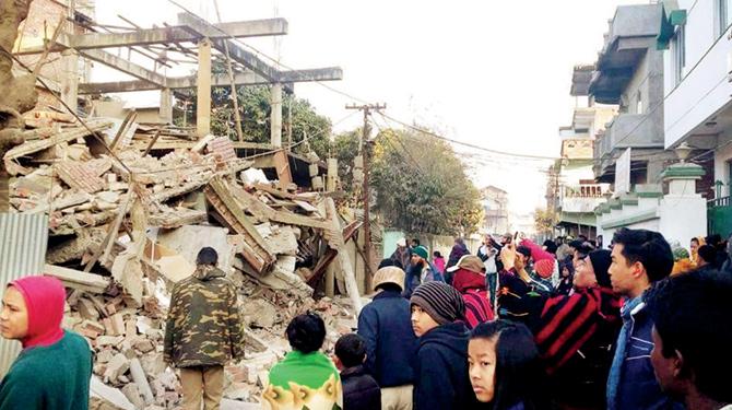 Residents gather near a collapsed building in Imphal. PIC/PTI
